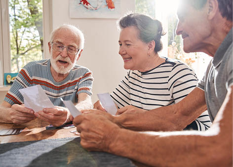 My memories. Three retirement people sitting at the table at the living room and watching at the old photos while spending their time at the nurse house